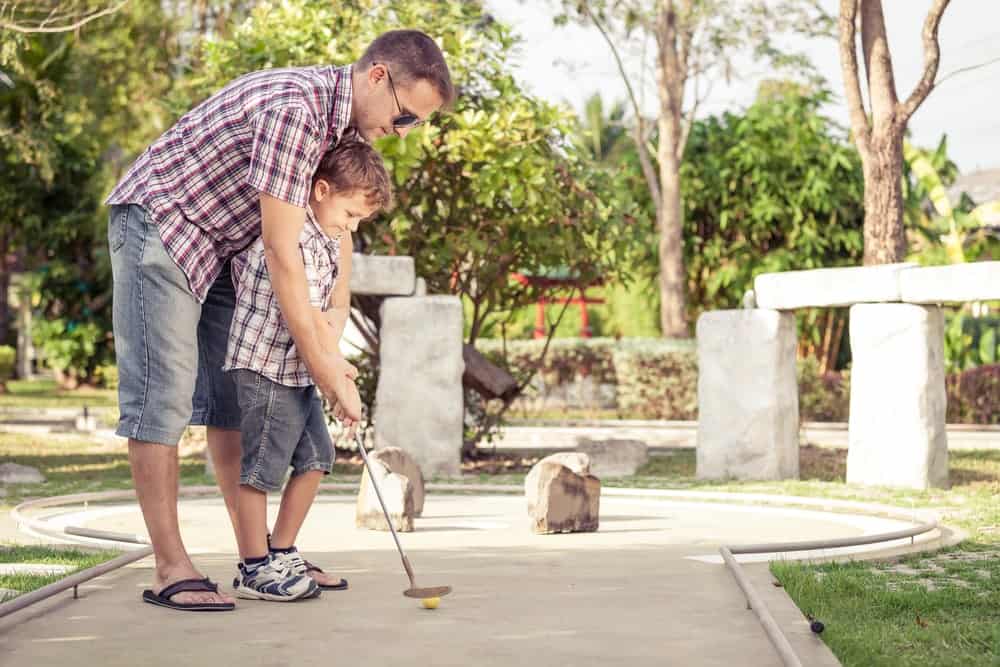 Father and son playing mini golf.