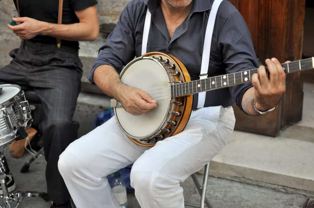 A banjo player and drummer performing on the street.
