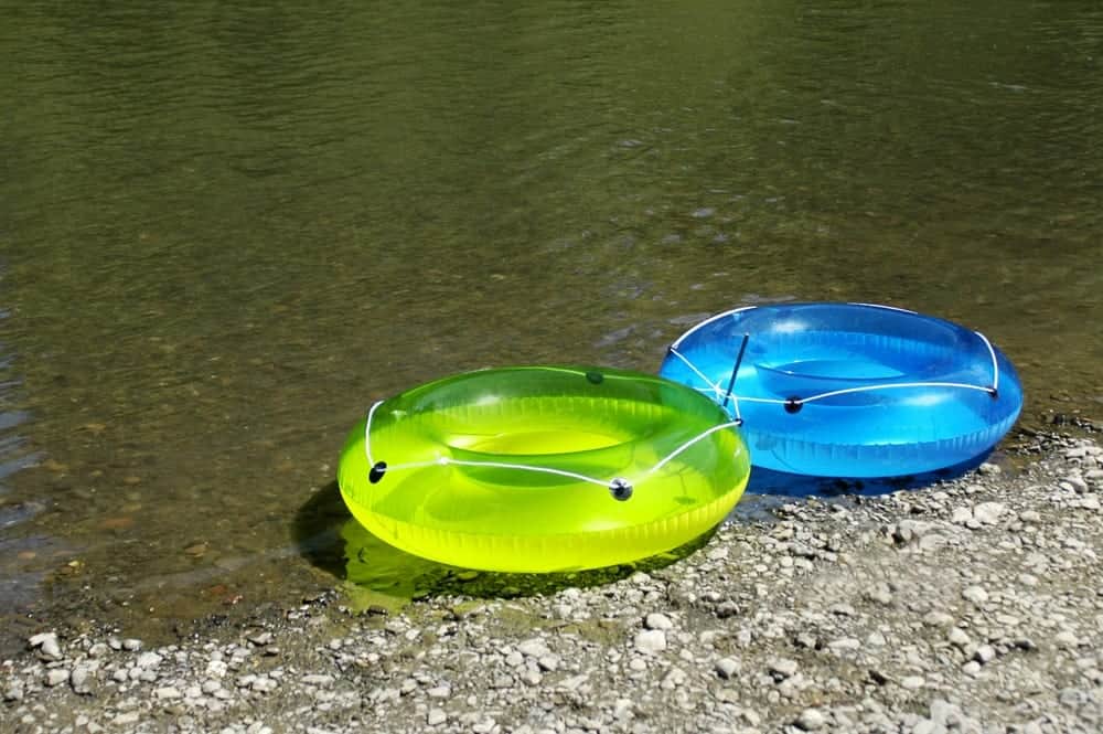 green and blue tubes on the bank of a river